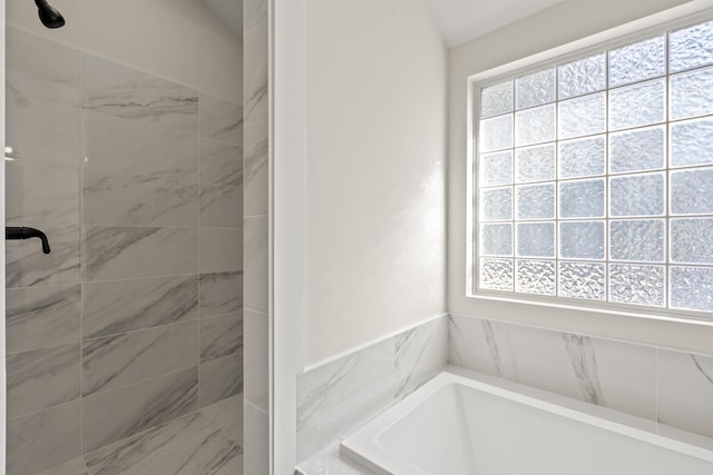 full bath with a garden tub and a tile shower