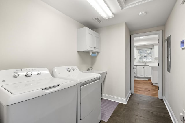 clothes washing area with cabinet space, baseboards, visible vents, separate washer and dryer, and a sink