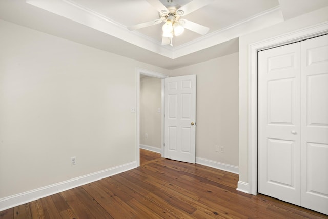 unfurnished bedroom with baseboards, dark wood-style floors, ceiling fan, crown molding, and a closet