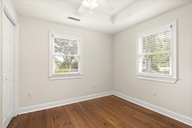 unfurnished room featuring a wealth of natural light, dark wood-type flooring, visible vents, and baseboards