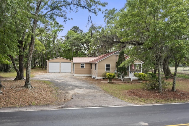 view of front of home with a porch, an outbuilding, metal roof, and a detached garage