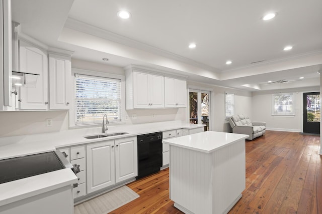 kitchen featuring a sink, black dishwasher, light wood-type flooring, a center island, and a raised ceiling