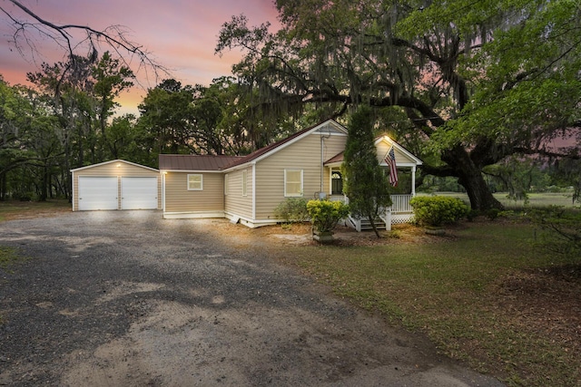 view of front of home with covered porch, an outdoor structure, a detached garage, and metal roof