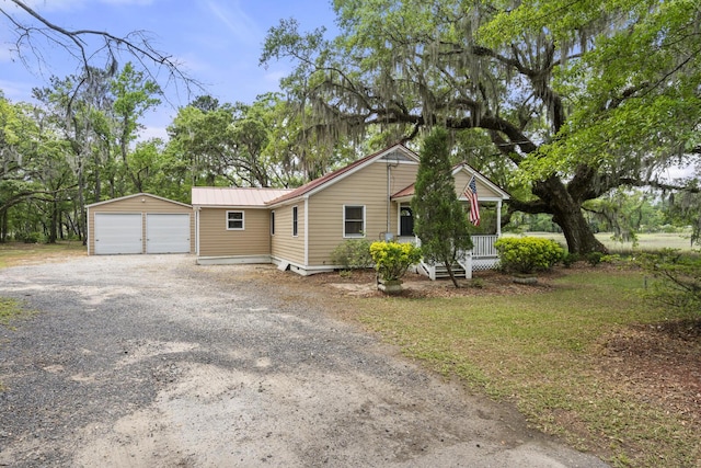 view of front of home featuring a garage, covered porch, an outdoor structure, and metal roof