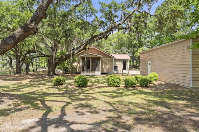 exterior space with metal roof and a yard