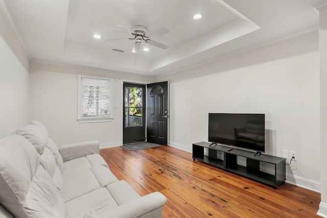 living area with a raised ceiling, visible vents, baseboards, and hardwood / wood-style floors