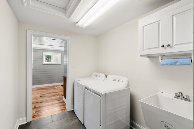 laundry room with cabinet space, baseboards, independent washer and dryer, tile patterned flooring, and a sink