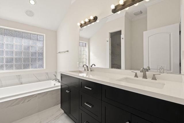 bathroom featuring lofted ceiling, a garden tub, double vanity, and a sink