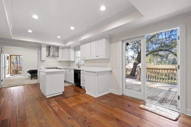 kitchen with black dishwasher, wall chimney exhaust hood, and a raised ceiling