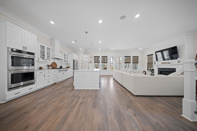 kitchen with white cabinetry, crown molding, open floor plan, and stainless steel appliances