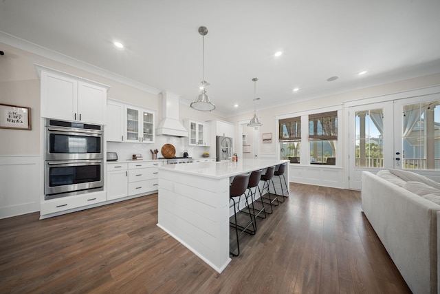 kitchen featuring custom range hood, an island with sink, dark wood-style floors, and stainless steel appliances