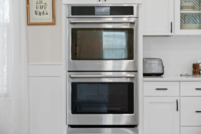 kitchen featuring decorative backsplash, white cabinets, double oven, and light countertops