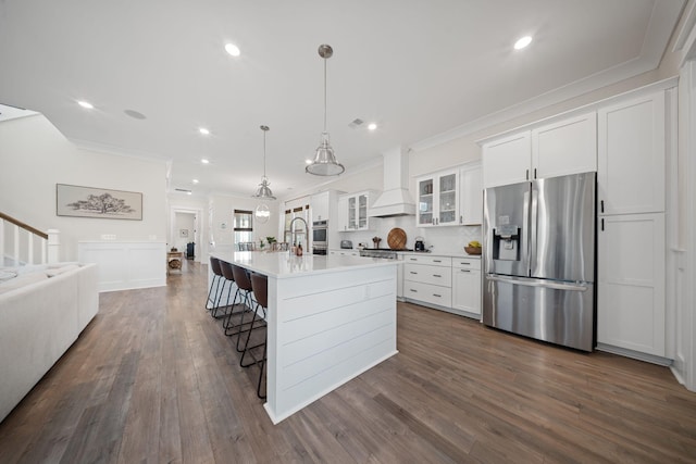 kitchen featuring premium range hood, ornamental molding, stainless steel appliances, white cabinets, and open floor plan