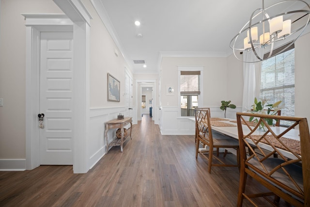 dining area with visible vents, dark wood-type flooring, a notable chandelier, ornamental molding, and a decorative wall