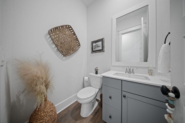 bathroom with vanity, toilet, wood finished floors, and baseboards