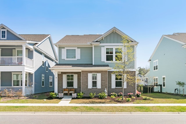 view of front of house featuring a balcony, a front lawn, and covered porch