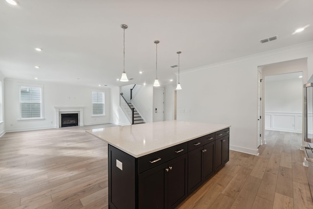 kitchen featuring pendant lighting, a center island, light hardwood / wood-style floors, and crown molding