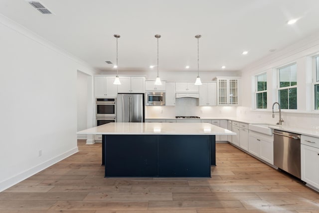 kitchen with pendant lighting, light wood-type flooring, stainless steel appliances, and a kitchen island