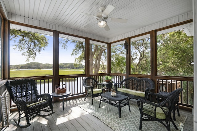 sunroom / solarium with ceiling fan and a water view