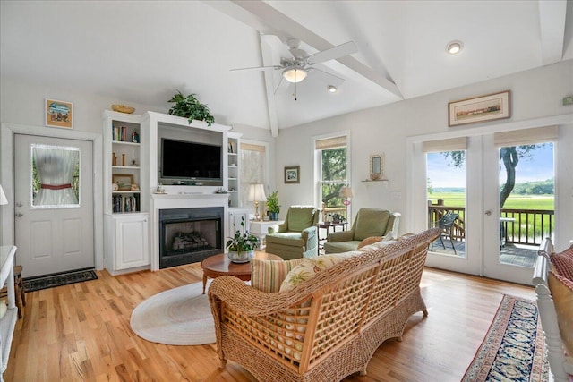 living room featuring light hardwood / wood-style flooring, vaulted ceiling with beams, ceiling fan, and french doors