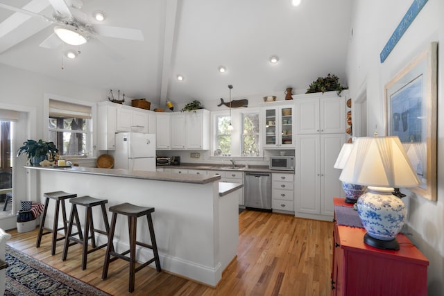 kitchen featuring kitchen peninsula, white cabinets, a breakfast bar, light hardwood / wood-style floors, and stainless steel appliances