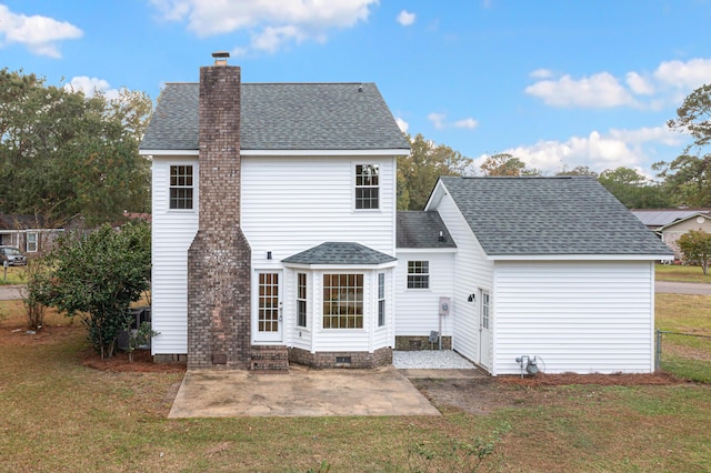rear view of property featuring a shingled roof, entry steps, a lawn, a chimney, and a patio