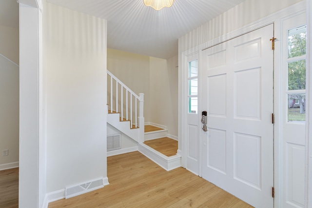 foyer entrance featuring visible vents, light wood-type flooring, stairway, and baseboards