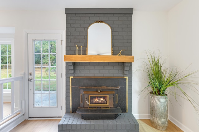 interior details with wood finished floors, baseboards, and a brick fireplace