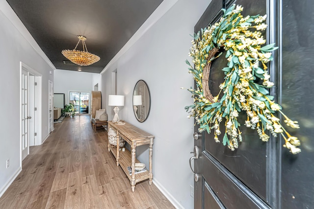 foyer featuring baseboards, crown molding, visible vents, and light wood finished floors