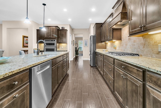 kitchen with pendant lighting, dark brown cabinets, dark hardwood / wood-style floors, custom range hood, and appliances with stainless steel finishes