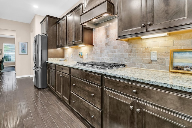 kitchen featuring custom range hood, dark wood-type flooring, light stone counters, stainless steel appliances, and dark brown cabinets