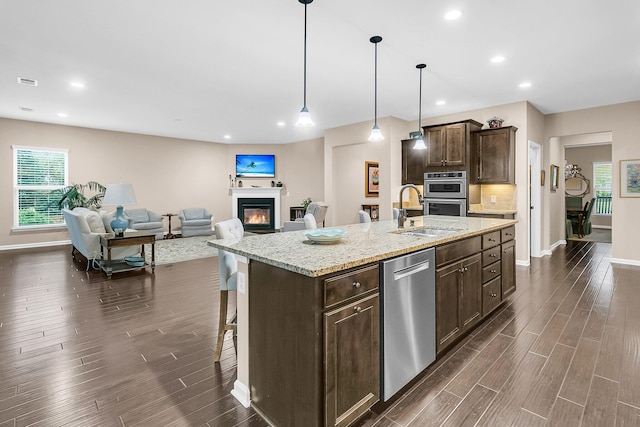 kitchen featuring sink, a kitchen breakfast bar, stainless steel appliances, a center island with sink, and decorative light fixtures