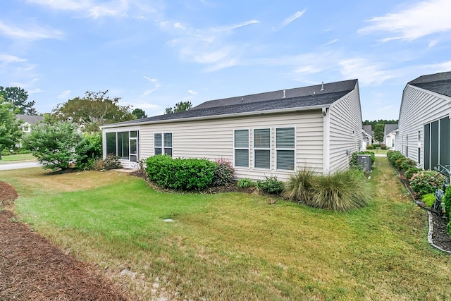 rear view of house featuring cooling unit, a sunroom, and a yard