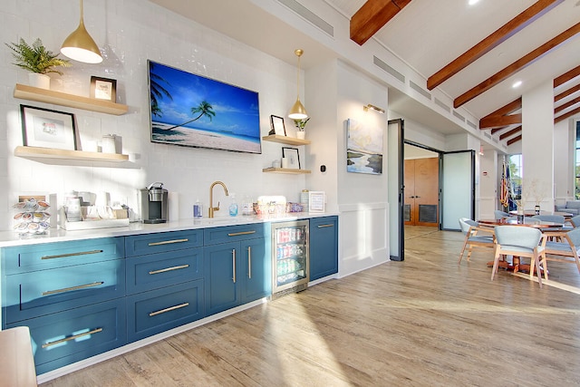 bar with light wood-type flooring, hanging light fixtures, beverage cooler, and sink