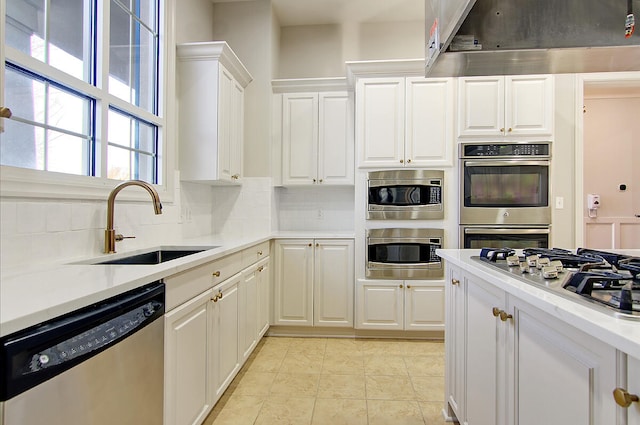 kitchen with appliances with stainless steel finishes, white cabinets, tasteful backsplash, ventilation hood, and sink