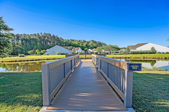 view of dock with a lawn and a water view