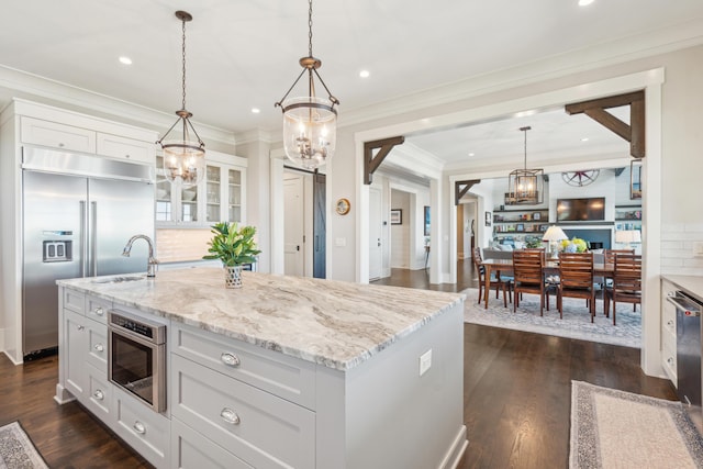 kitchen with white cabinets, light stone countertops, dark wood-style floors, and built in fridge