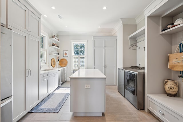 kitchen featuring open shelves, a center island, washing machine and dryer, freestanding refrigerator, and a sink