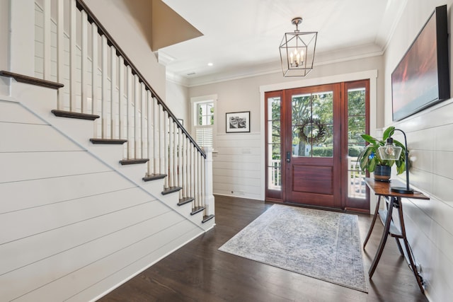 foyer with stairs, a notable chandelier, wood finished floors, and ornamental molding