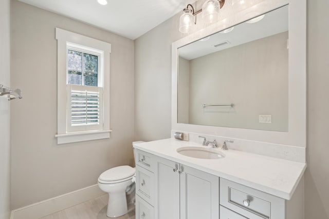 bathroom featuring visible vents, toilet, vanity, and baseboards