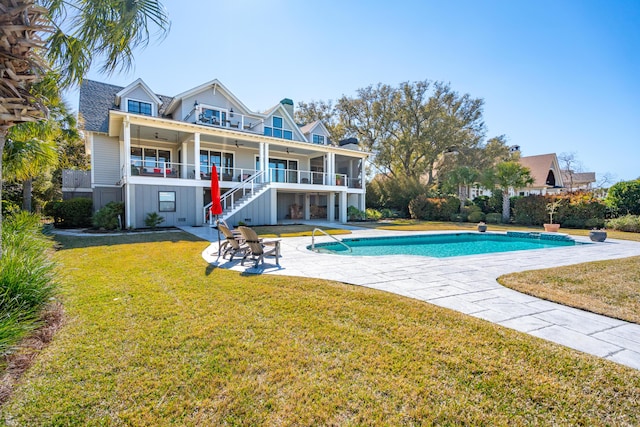 back of property with stairs, a yard, a patio area, and an outdoor pool