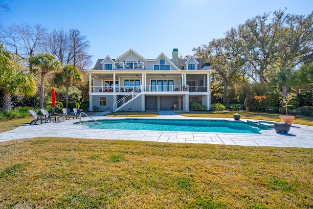 rear view of house featuring an outdoor pool, a lawn, stairs, and a patio area