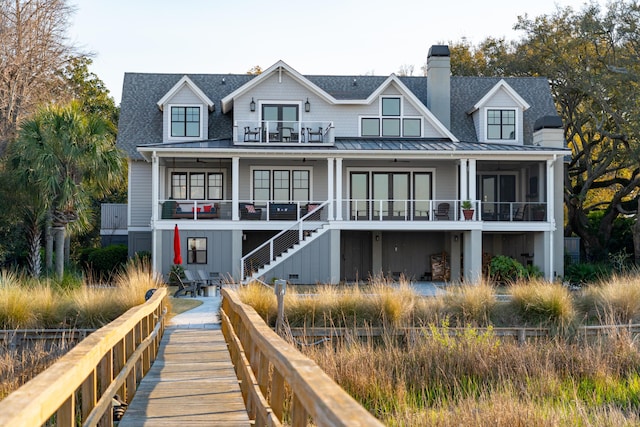 back of house featuring a balcony, a standing seam roof, a shingled roof, stairs, and metal roof