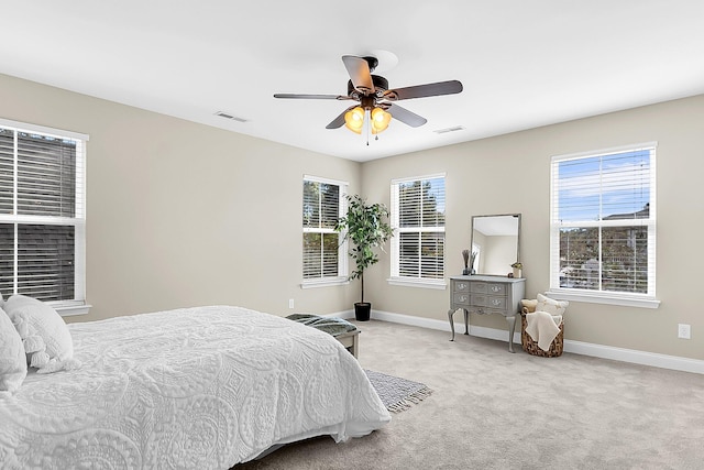 carpeted bedroom with ceiling fan and multiple windows