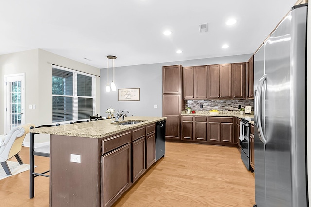 kitchen featuring sink, light hardwood / wood-style flooring, black appliances, and decorative light fixtures