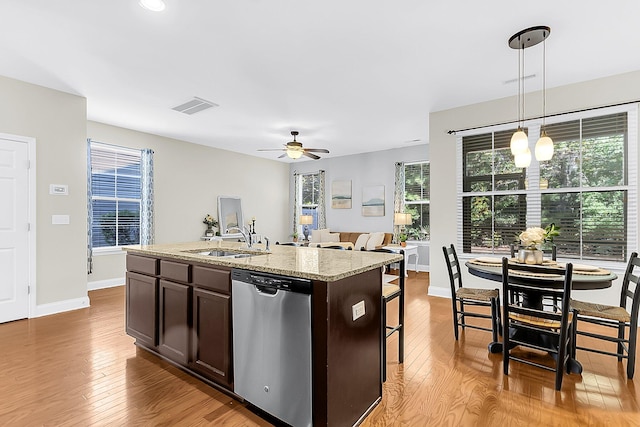 kitchen with a kitchen island with sink, sink, decorative light fixtures, stainless steel dishwasher, and light hardwood / wood-style floors