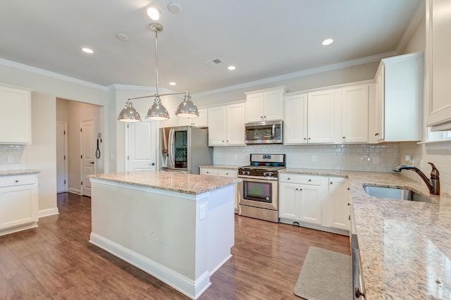 kitchen featuring white cabinetry, sink, stainless steel appliances, light stone counters, and a kitchen island