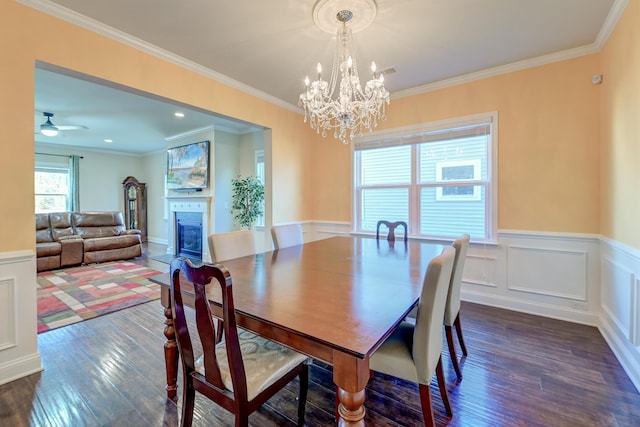 dining space featuring dark hardwood / wood-style floors, ornamental molding, and ceiling fan with notable chandelier