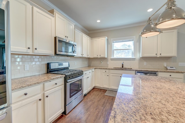 kitchen featuring white cabinetry, sink, hanging light fixtures, stainless steel appliances, and decorative backsplash