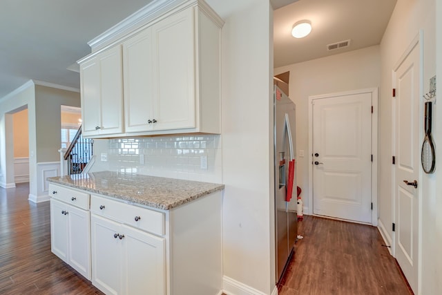 kitchen with stainless steel fridge, light stone counters, white cabinetry, and dark wood-type flooring